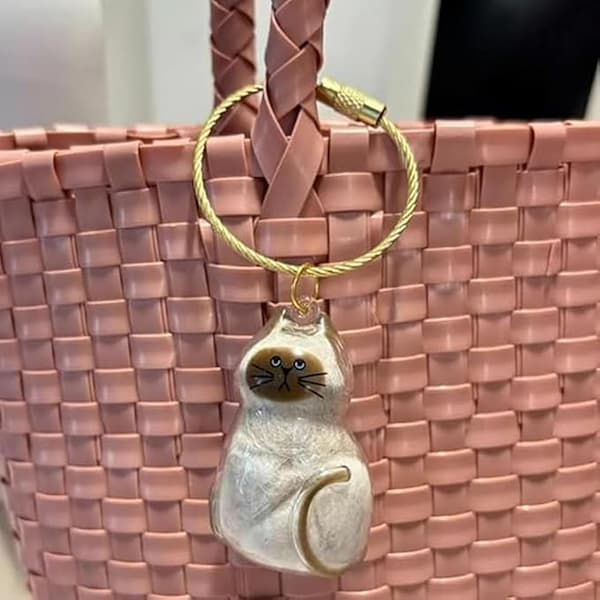 Cat-shaped keychain on a pink woven bag