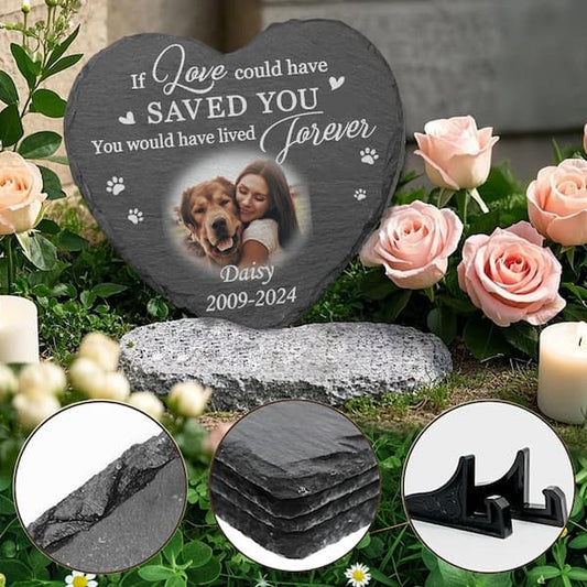 Heart-shaped memorial stone with photo of a woman and dog, surrounded by flowers and candles.