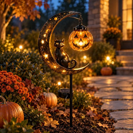 Solar Halloween garden stake with a black cat, crescent moon and glowing pumpkin beside an autumn pathway