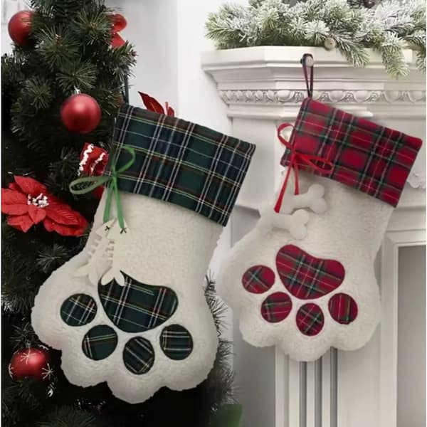 Two plaid Christmas stockings with paw designs hanging on a fireplace mantle.