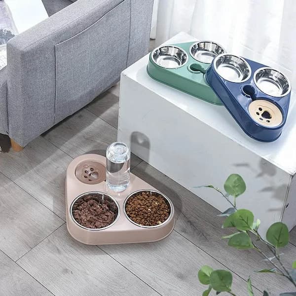 Pet feeding station with multiple bowls on a white table next to a gray sofa.