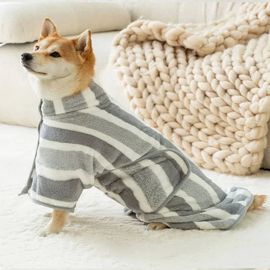 Medium dog wearing a gray and white striped absorbent bathrobe on a cozy bed.