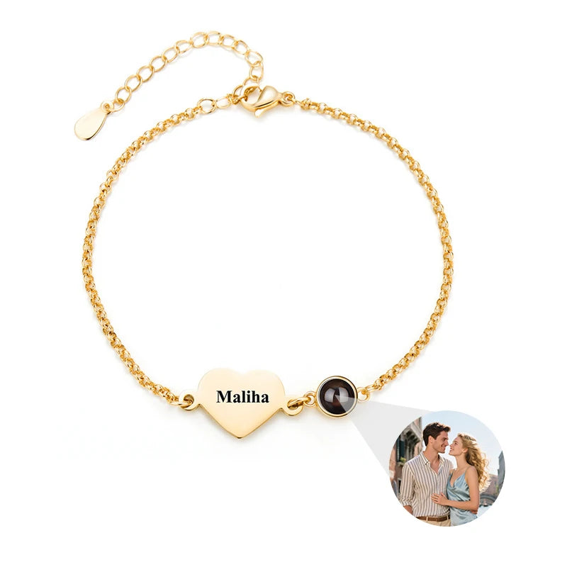 Gold bracelet with heart-shaped charm and photo charm on a white background