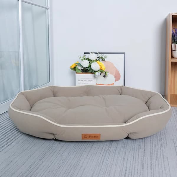 Beige pet bed in a room with a window and decorative items.