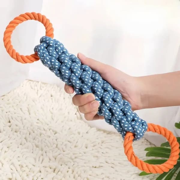 Blue dog toy with orange rings held by a hand on a white background