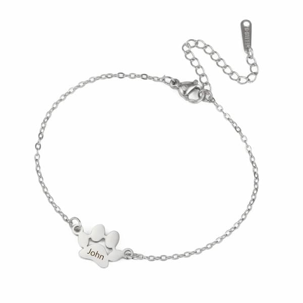 Silver bracelet with a paw-shaped tag and 'John' engraving on a white background
