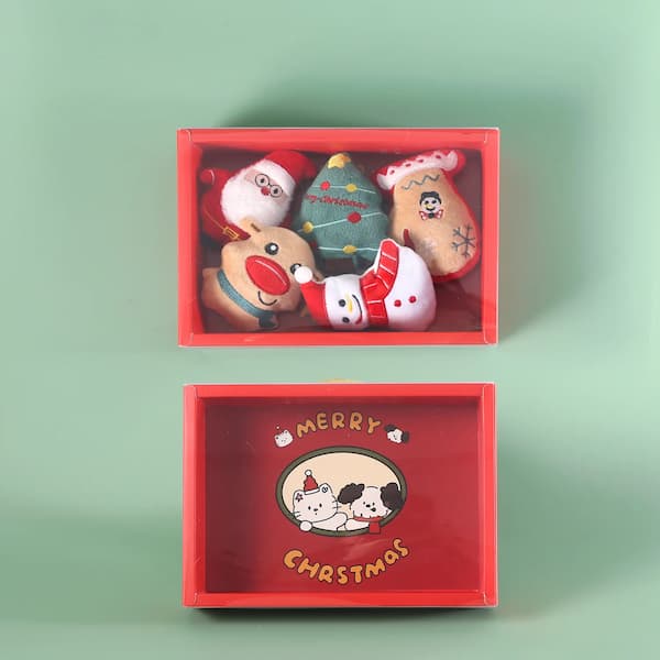 Red Christmas-themed gift box with festive cat toys on a green background