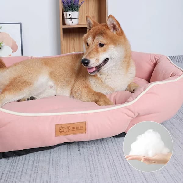 Dog lying on a pink pet bed with fluffy texture, surrounded by a cozy indoor setting.
