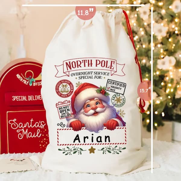Personalized Santa sack with Santa Claus design and 'North Pole' text, placed in front of a Christmas tree.