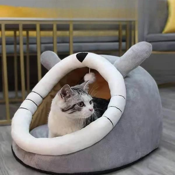 Cat inside a gray pet bed with bunny ears in a cozy room.