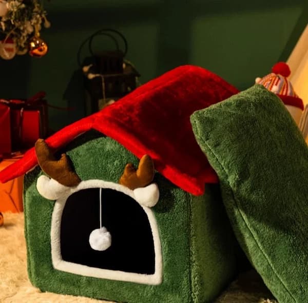 Green pet house with red roof and antlers in a festive setting