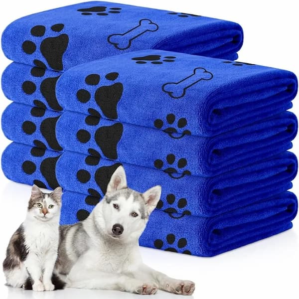 Stack of blue towels with black paw and bone prints, featuring a cat and dog in front.