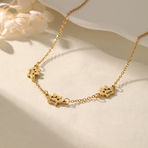 Gold necklace with paw-shaped pendants on a light background