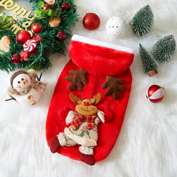 Red Christmas pet hoodie with reindeer design surrounded by festive decorations on a white surface.