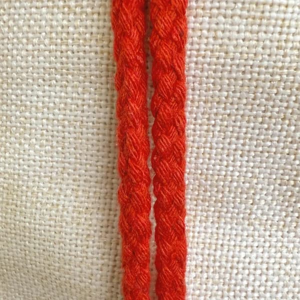 Red braided cord on a beige fabric background