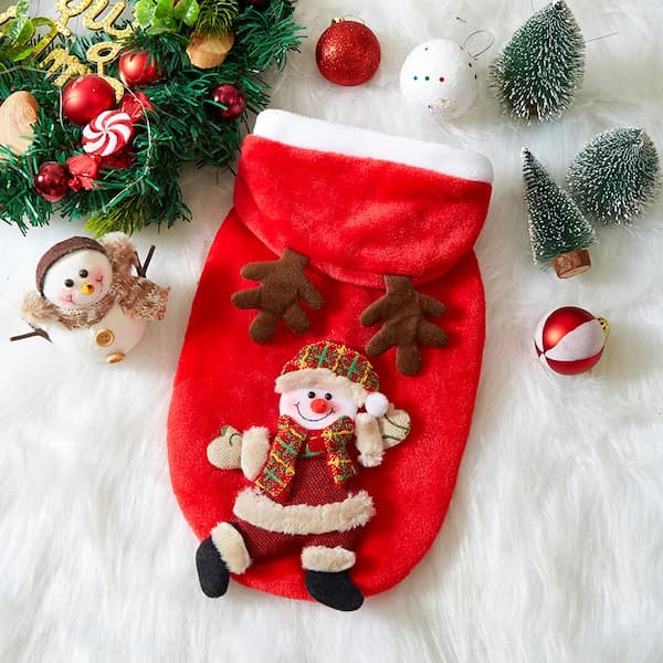 Red Christmas pet hoodie with Santa Claus design surrounded by festive decorations on a white surface.