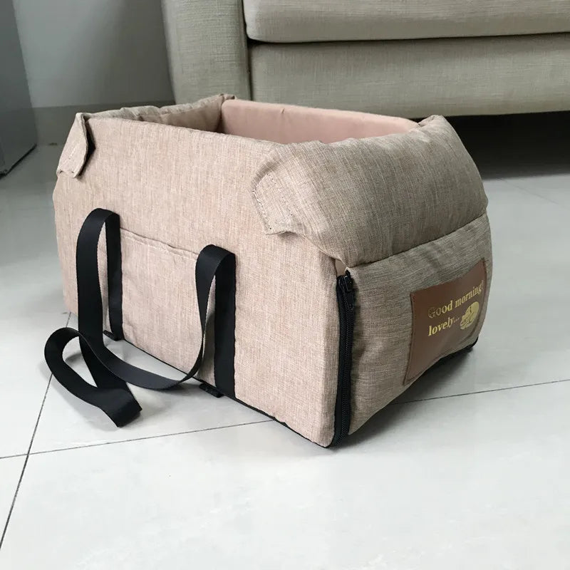 Beige pet carrier with black straps on a white floor.