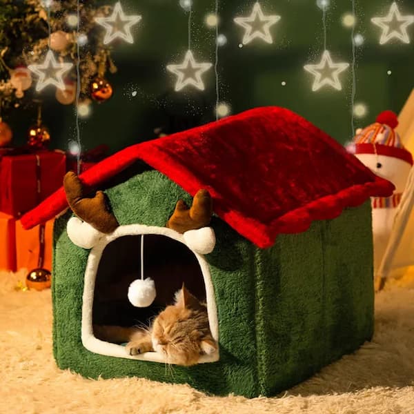 Green pet house with red roof and reindeer ears, featuring a cat inside, set against a festive background with stars and lights.