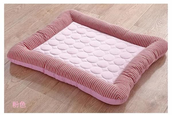 Pink pet cooling bed with quilted design on a wooden floor