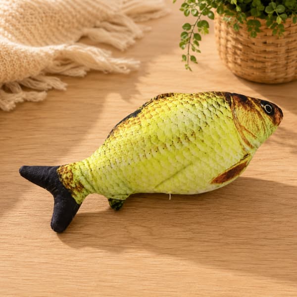 Realistic golden carp plush cat toy displayed on a wooden table in a cozy indoor setting for cats and kittens