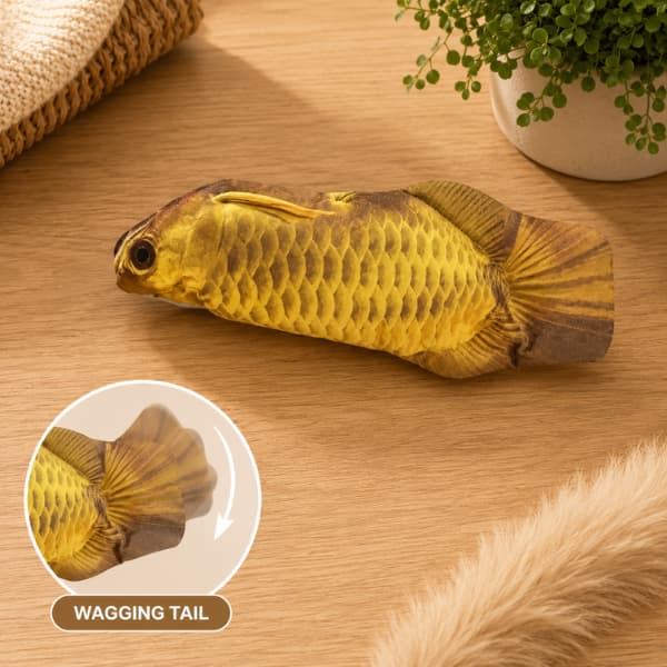 Interactive golden fish plush cat toy with wagging tail displayed on a wooden table in a cozy indoor setting for cats and kittens