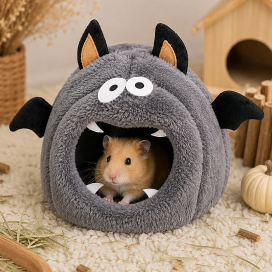 Golden hamster resting inside a grey Halloween bat small pet hideaway with soft fleece interior.