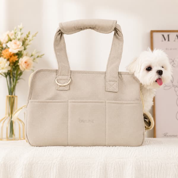 Luxury beige pet travel carrier bag with a fluffy white puppy sitting inside in a cozy modern indoor setting