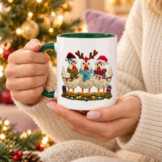 Dark green-handled mug featuring three festive chickens, held in two hands beside a softly lit Christmas tree.