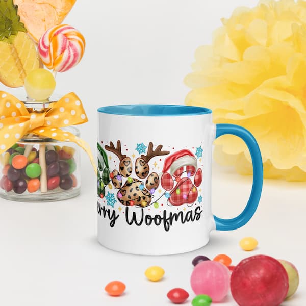 Mug with Christmas-themed design featuring paw prints and text, surrounded by colorful candies and flowers.