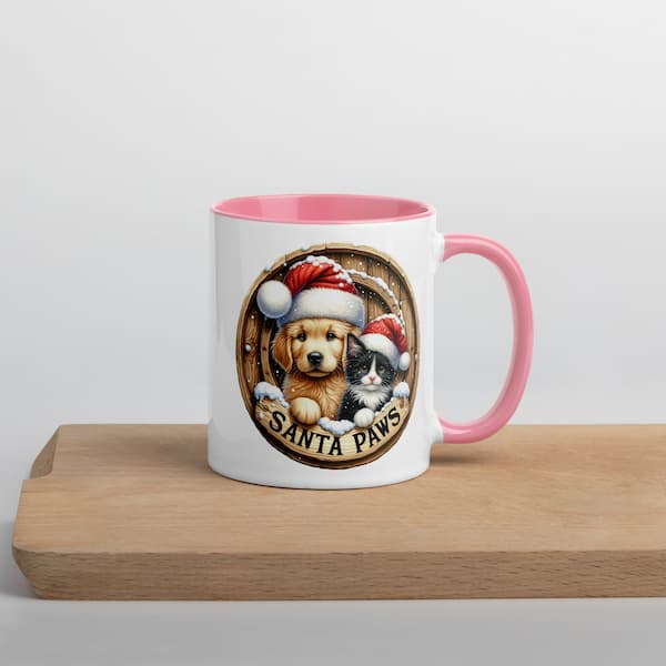 Mug with a design of a dog and cat wearing Santa hats on a wooden surface.