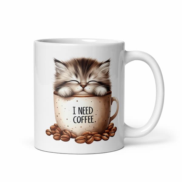 Cute fluffy kitten sleeping inside a coffee mug with the words “I Need Coffee” surrounded by coffee beans – ceramic cat lover gift mug.