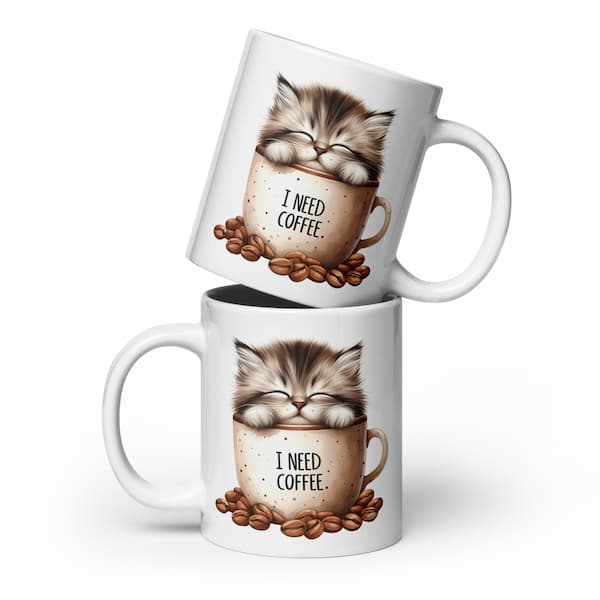 Two white mugs with a cat illustration and 'I Need Coffee' text, stacked on a white background.
